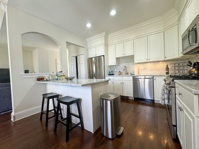 kitchen featuring white cabinetry, appliances with stainless steel finishes, decorative backsplash, and dark wood-style flooring