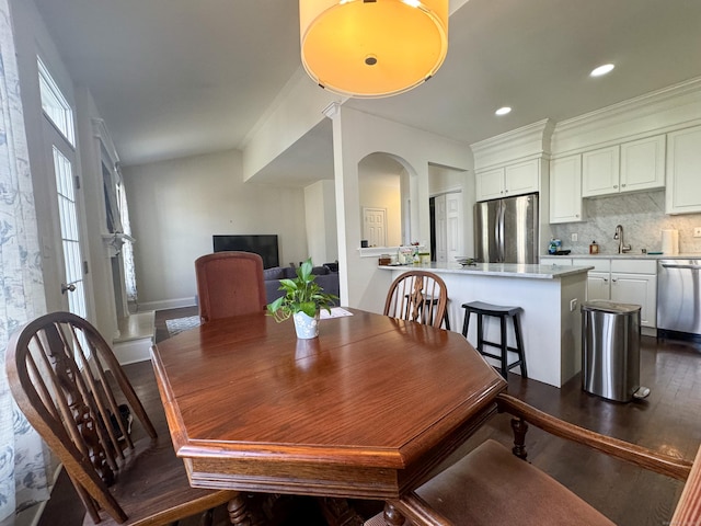 dining room with recessed lighting, dark wood-style flooring, and arched walkways