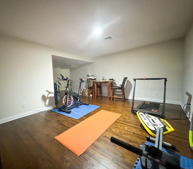 workout area featuring baseboards, visible vents, and wood finished floors