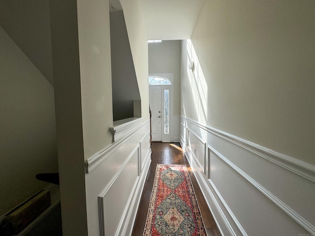 corridor featuring a wainscoted wall, dark wood finished floors, and a decorative wall