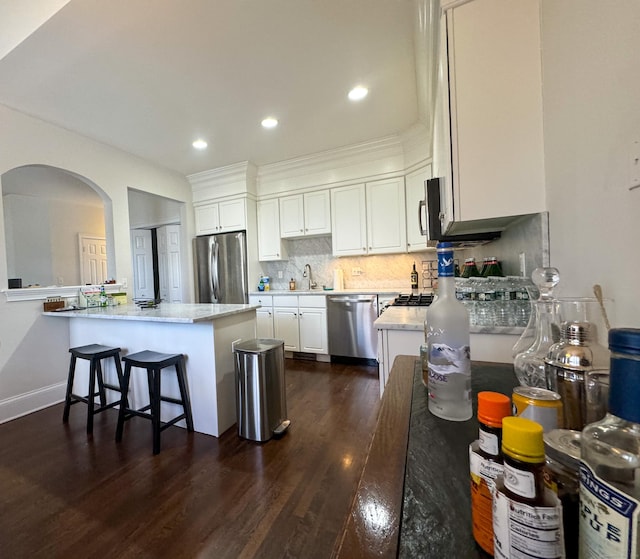 kitchen featuring dark wood-style floors, stainless steel appliances, backsplash, white cabinetry, and a sink