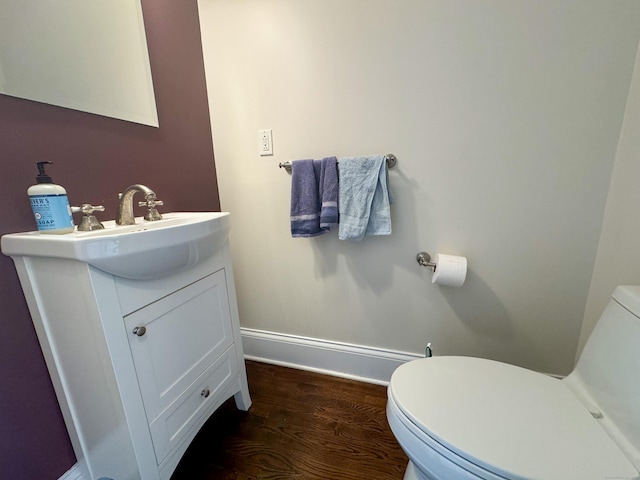 half bathroom with toilet, baseboards, wood finished floors, and vanity