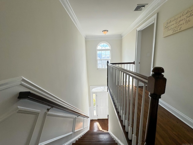 staircase featuring baseboards, visible vents, ornamental molding, wood finished floors, and a high ceiling