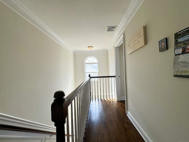 hallway featuring baseboards, visible vents, dark wood-style floors, ornamental molding, and an upstairs landing