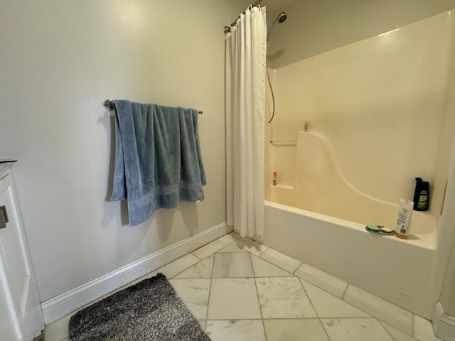 bathroom with marble finish floor, shower / bath combo with shower curtain, and baseboards