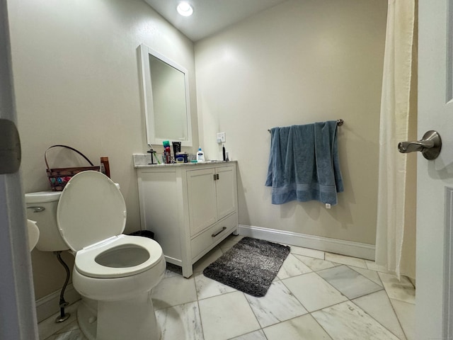 bathroom featuring toilet, marble finish floor, baseboards, and vanity