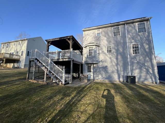 back of property with central air condition unit, stairway, a yard, and a wooden deck