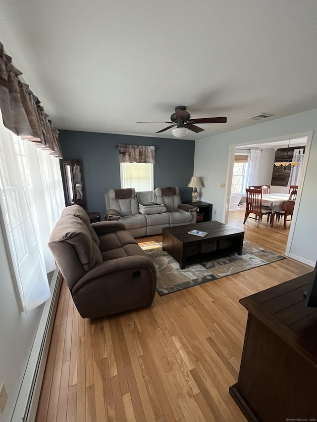 living area with visible vents, light wood-style floors, ceiling fan, and a baseboard radiator