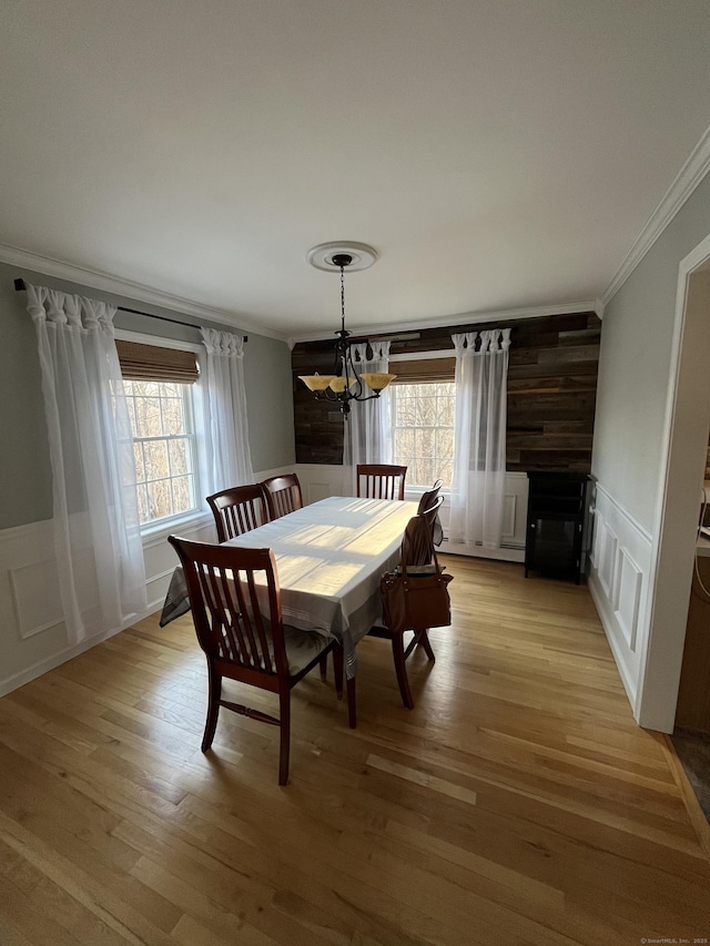 dining area with a notable chandelier, plenty of natural light, light wood-type flooring, and crown molding