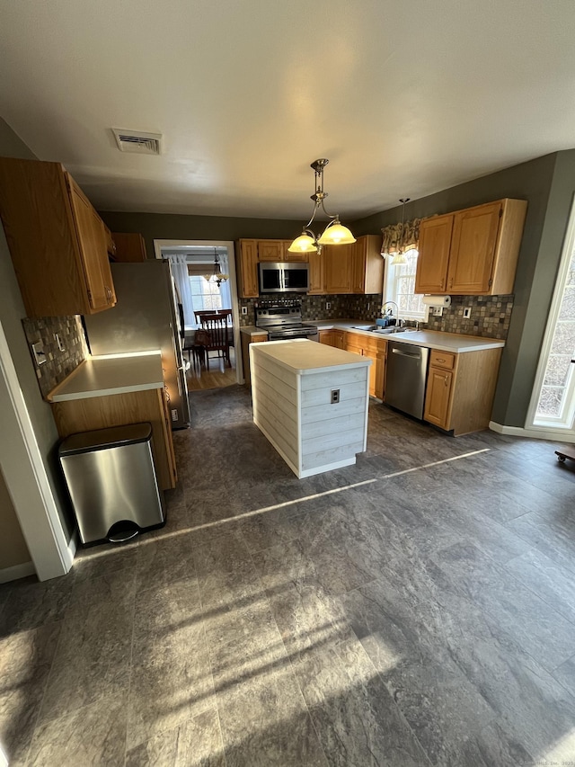 kitchen with a wealth of natural light, a sink, backsplash, stainless steel appliances, and light countertops