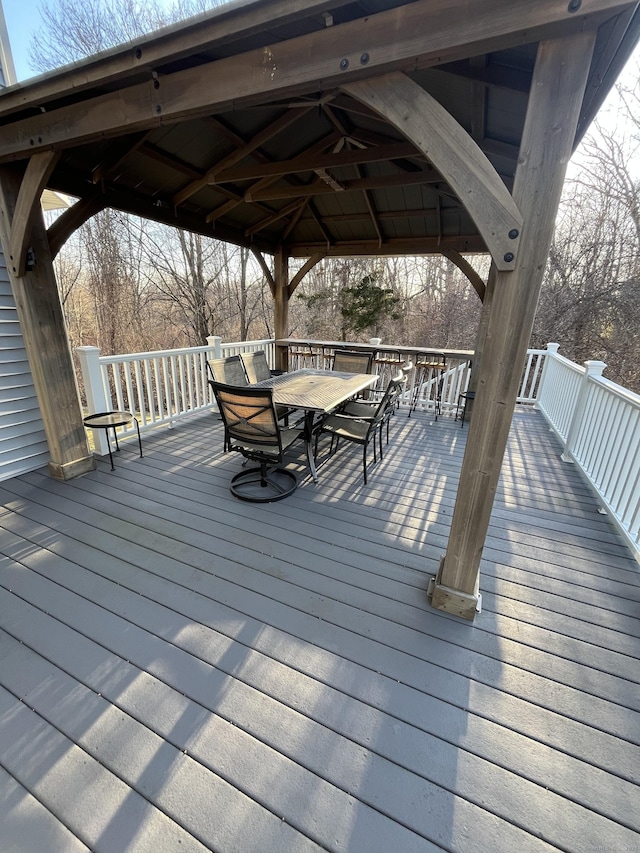 wooden deck with a gazebo, outdoor dining area, and a ceiling fan