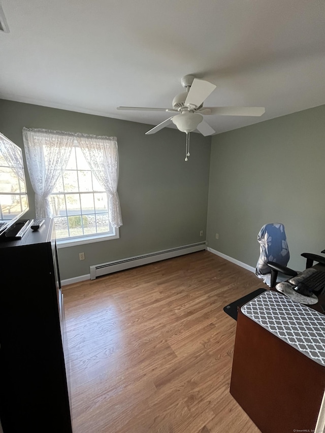 home office featuring a baseboard heating unit, baseboards, light wood-style flooring, and a ceiling fan