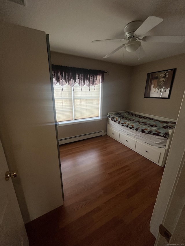 unfurnished bedroom featuring wood finished floors, baseboard heating, and ceiling fan