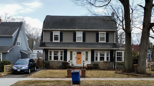 view of front of property with a shingled roof, fence, and a chimney