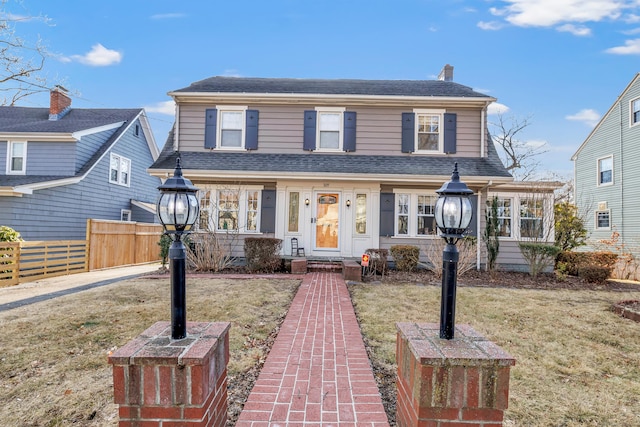 view of front of home featuring a shingled roof, a front yard, and fence