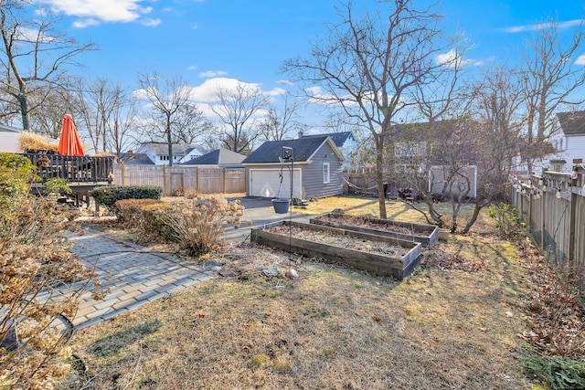 view of yard with a fenced backyard, a garage, an outdoor structure, driveway, and a vegetable garden