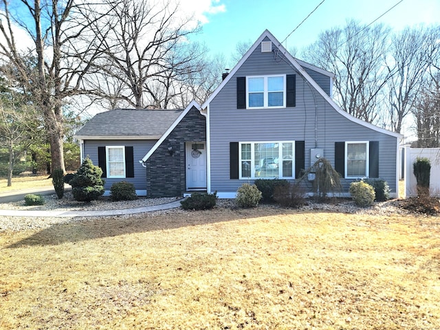 view of front of home with a front yard, fence, stone siding, and a chimney