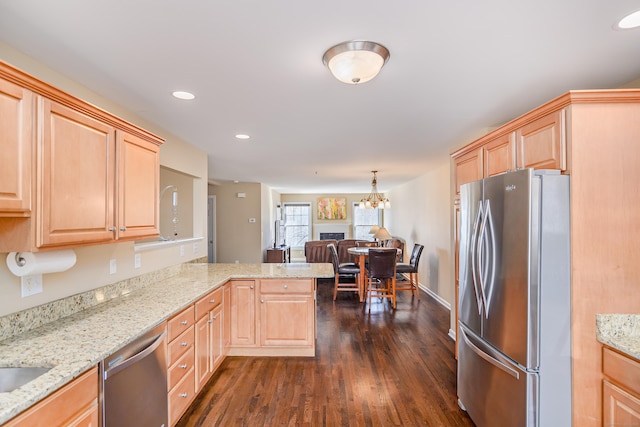 kitchen with a peninsula, light brown cabinets, dark wood-style flooring, and appliances with stainless steel finishes