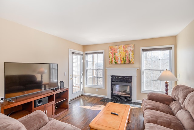 living area featuring a high end fireplace, plenty of natural light, baseboards, and dark wood-style flooring