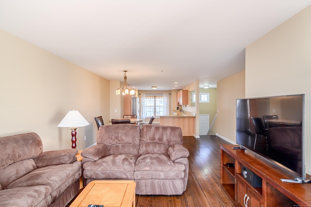 living area with an inviting chandelier, dark wood-style floors, and baseboards