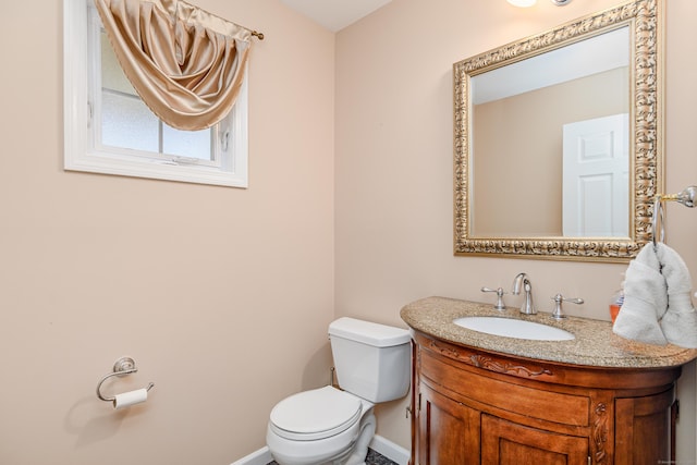 half bathroom featuring baseboards, toilet, and vanity