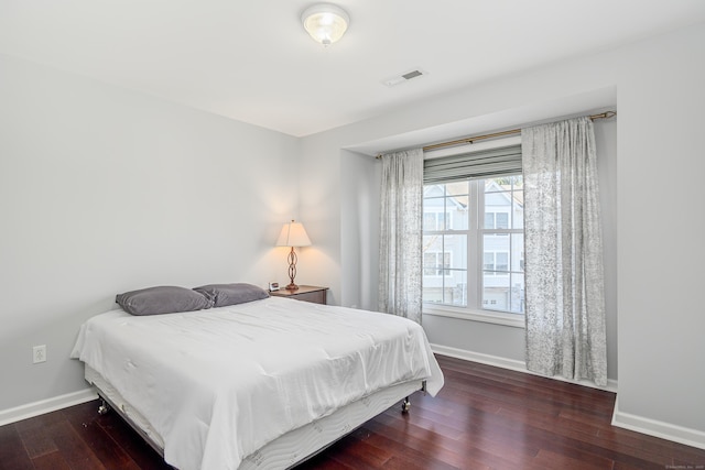 bedroom with wood finished floors, visible vents, and baseboards