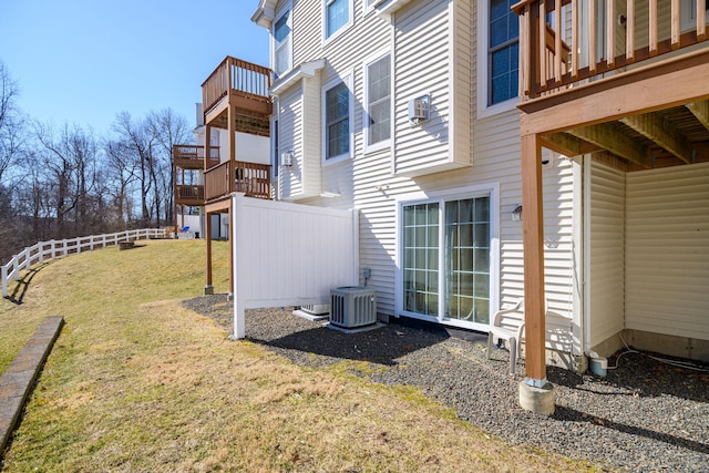 view of side of home featuring central air condition unit, a lawn, and fence