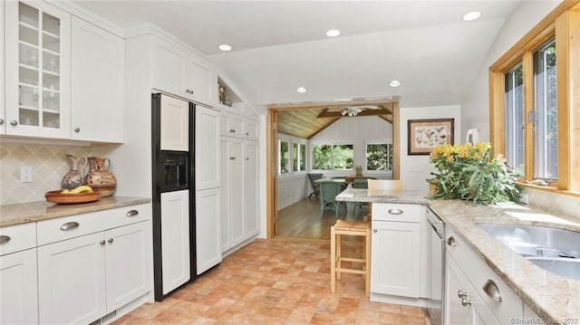 kitchen with glass insert cabinets, vaulted ceiling, decorative backsplash, white cabinetry, and paneled refrigerator