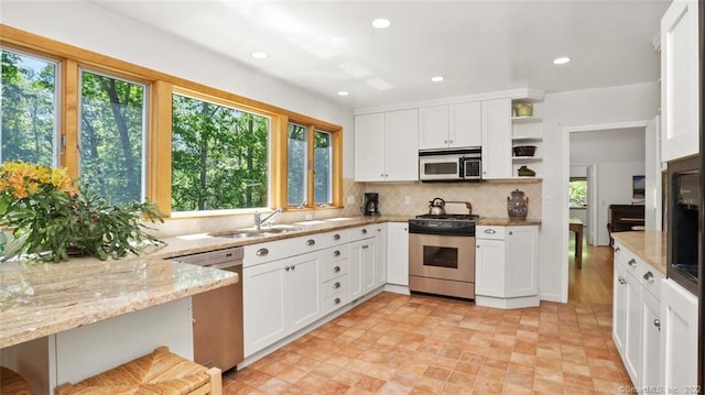 kitchen with open shelves, light stone countertops, appliances with stainless steel finishes, and white cabinets