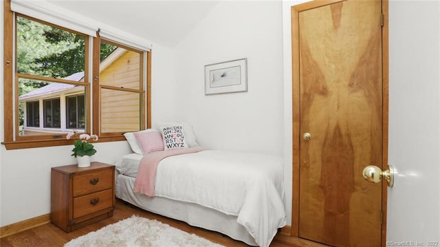 bedroom featuring vaulted ceiling, wood finished floors, and baseboards