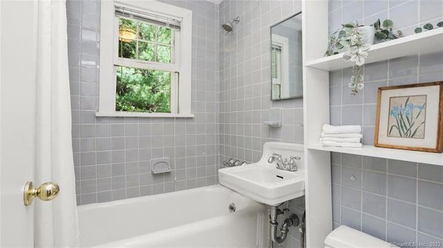 bathroom featuring tile walls, shower / bathtub combination with curtain, and a sink