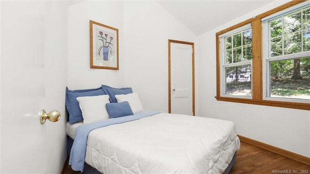 bedroom featuring baseboards, dark wood-type flooring, and vaulted ceiling