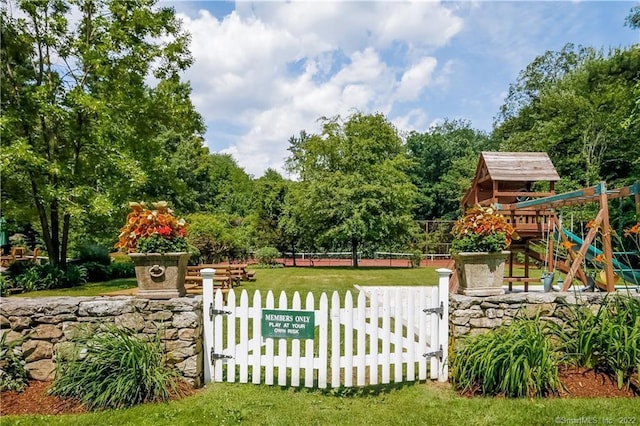 community sign featuring a yard, fence, and a gate