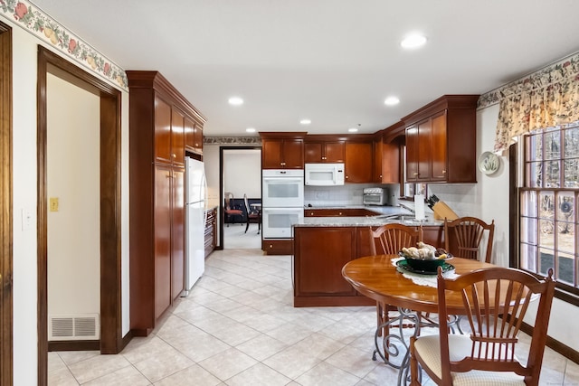 kitchen with visible vents, white appliances, plenty of natural light, and a peninsula