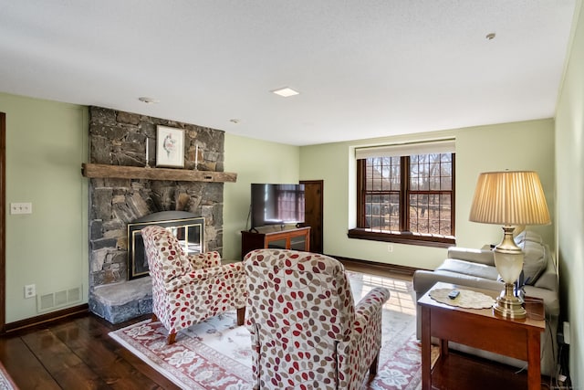 living room with a fireplace, wood finished floors, visible vents, and baseboards