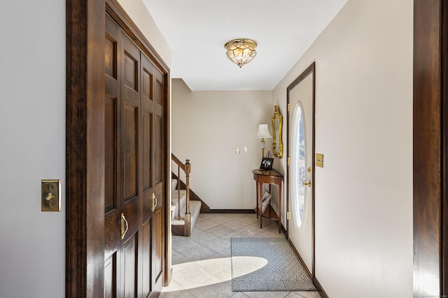 entrance foyer featuring stairs, light tile patterned floors, and baseboards