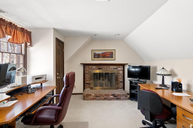 carpeted home office with a brick fireplace and vaulted ceiling