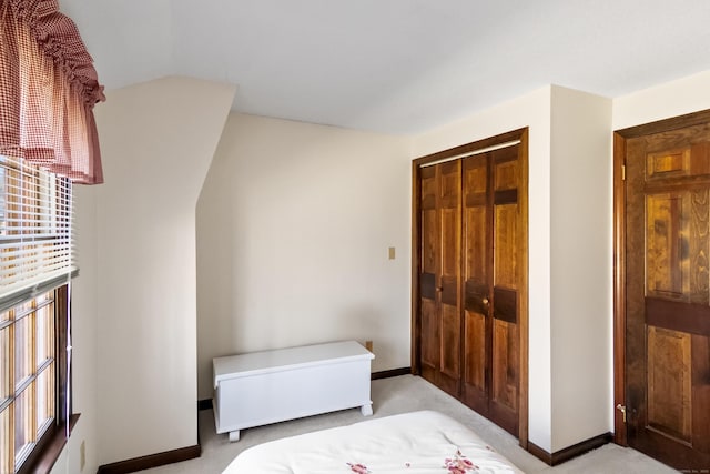 bedroom with a closet, light carpet, and baseboards