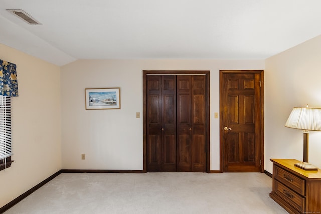 bedroom featuring visible vents, baseboards, vaulted ceiling, a closet, and light colored carpet