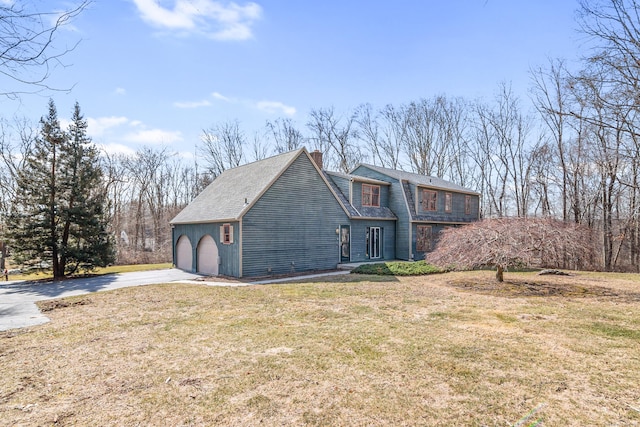 view of front of home with a front lawn, concrete driveway, a garage, and a chimney