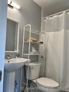 full bath with a shower with shower curtain, toilet, and a sink