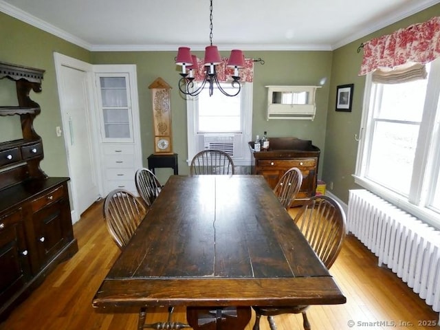 dining space featuring a notable chandelier, ornamental molding, radiator, and wood finished floors