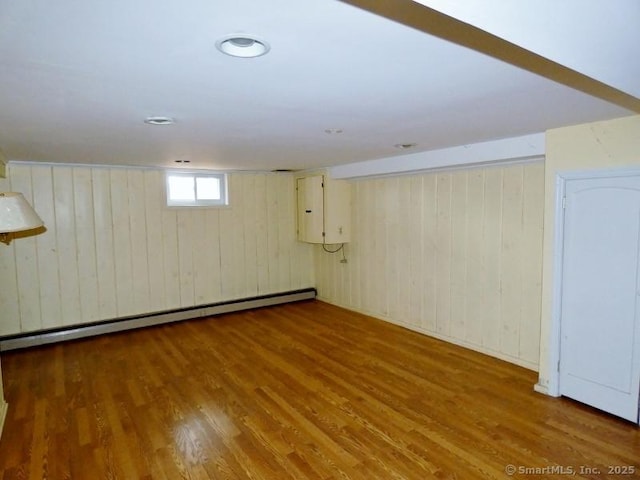 below grade area with electric panel, wood finished floors, and a baseboard radiator