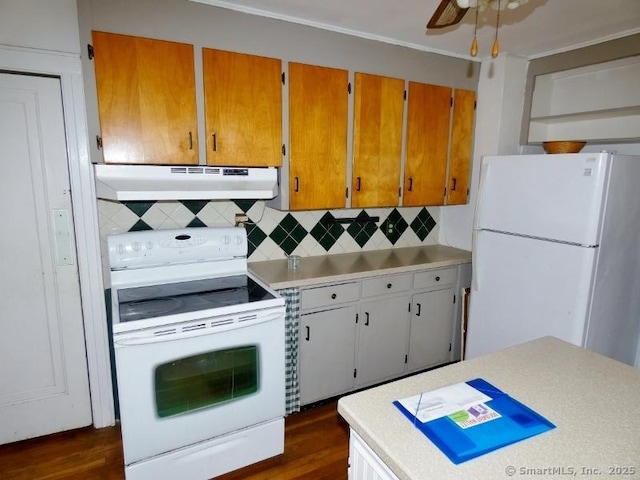 kitchen with dark wood-type flooring, under cabinet range hood, backsplash, white appliances, and light countertops