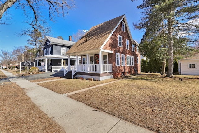 view of side of home with a lawn, a porch, and roof with shingles