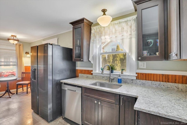 kitchen featuring dark brown cabinetry, appliances with stainless steel finishes, glass insert cabinets, and a sink