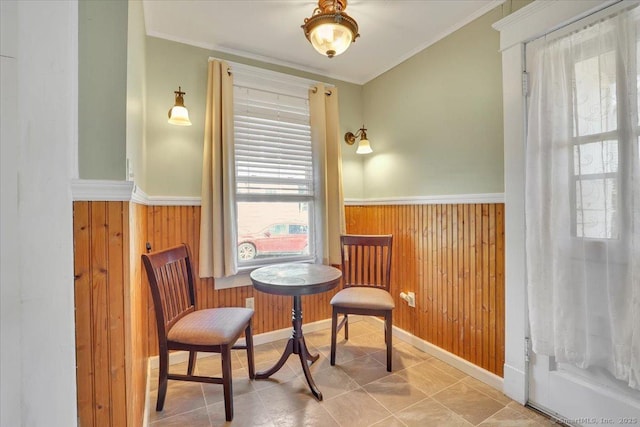 sitting room with a wainscoted wall, wood walls, and crown molding