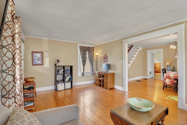 living room with light wood-style flooring, stairs, baseboards, and ornamental molding