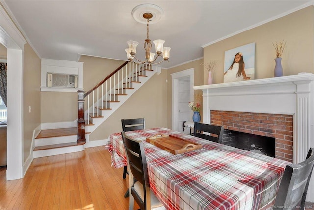 dining area with crown molding, baseboards, stairs, a wall unit AC, and light wood-style floors