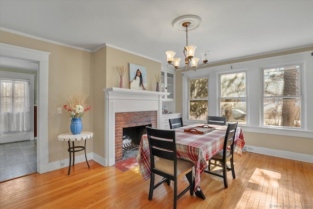 dining room with light wood-type flooring, plenty of natural light, an inviting chandelier, and crown molding